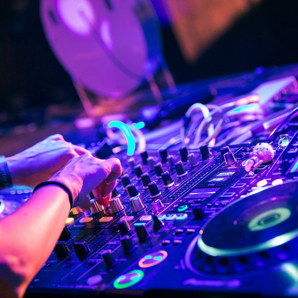 Tangan DJ di controller dengan lampu ungu
